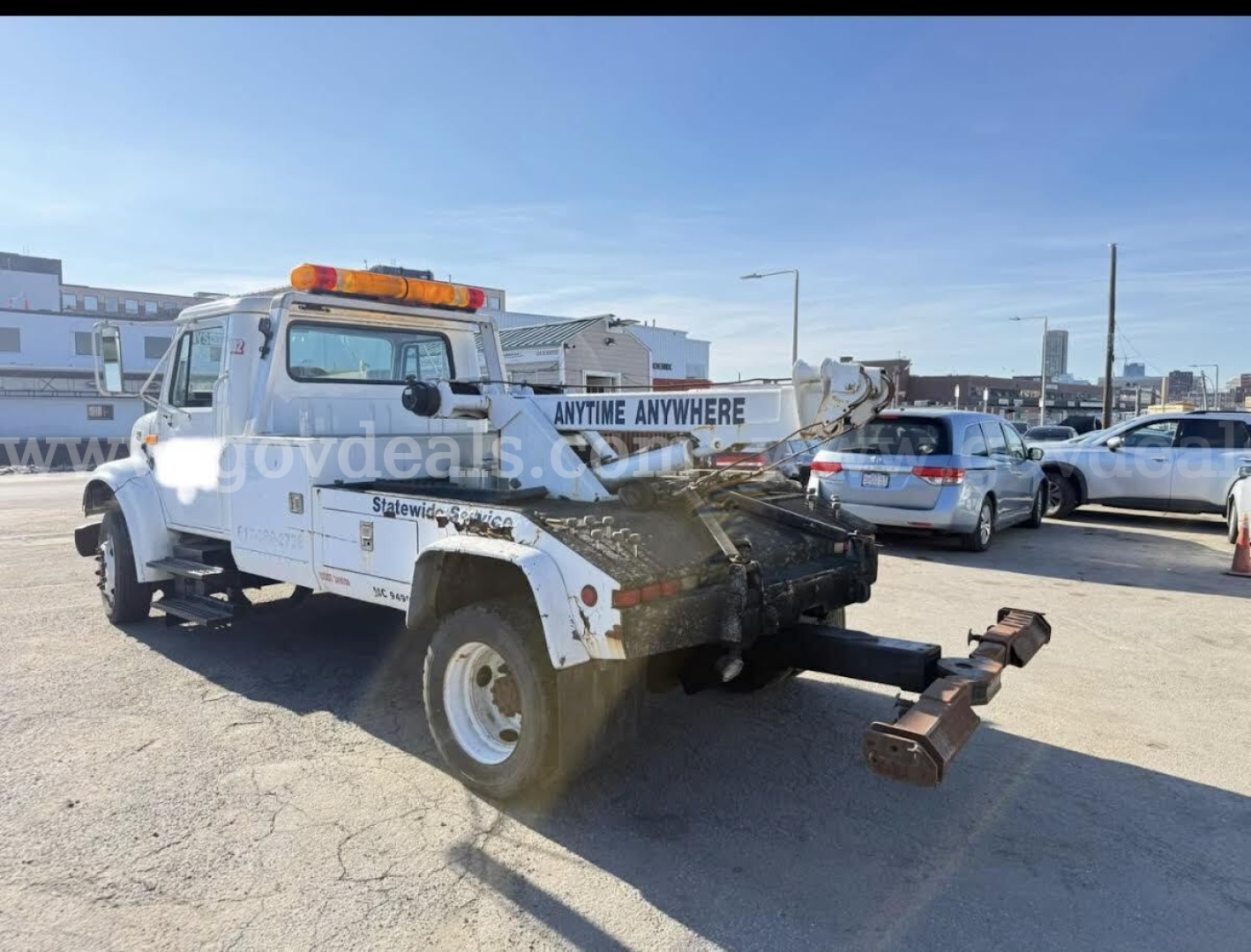 Tow truck rear quarter view showing towing arm and winch with amber beacon light on cab roof, International 4700, VIN 1HTSCABM7TH248809, stock 30619-1.