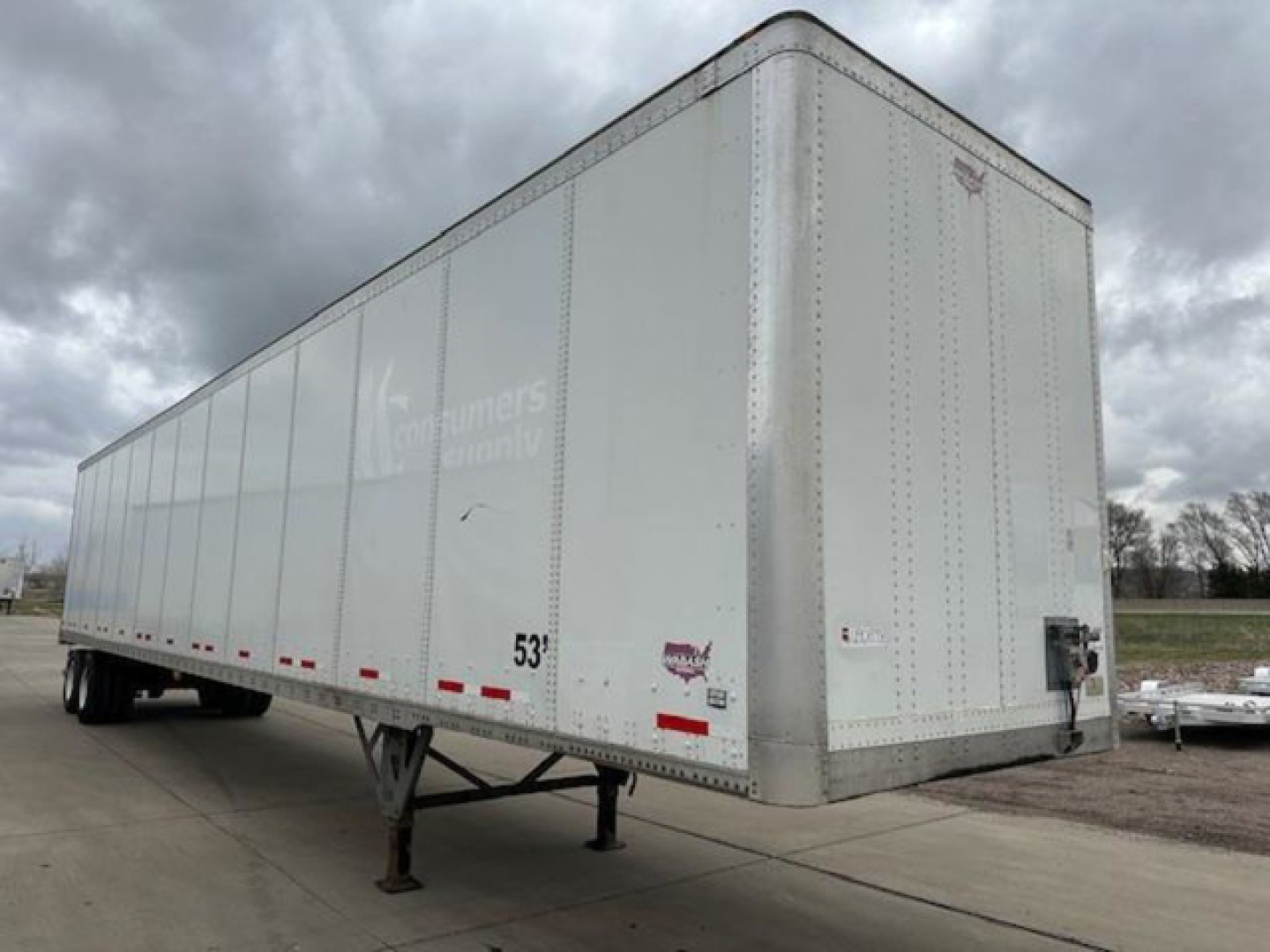 Trailer side and front of a white 2016 Wabash van trailer showing side stakes and support legs with 53’ length, used condition; visible VIN label and stock number.