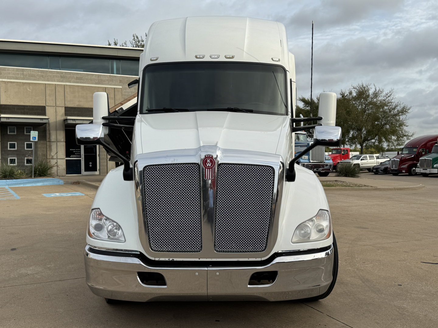 Kenworth T680 front view showing large dual grille and windshield, chrome bumper, and large side mirrors.