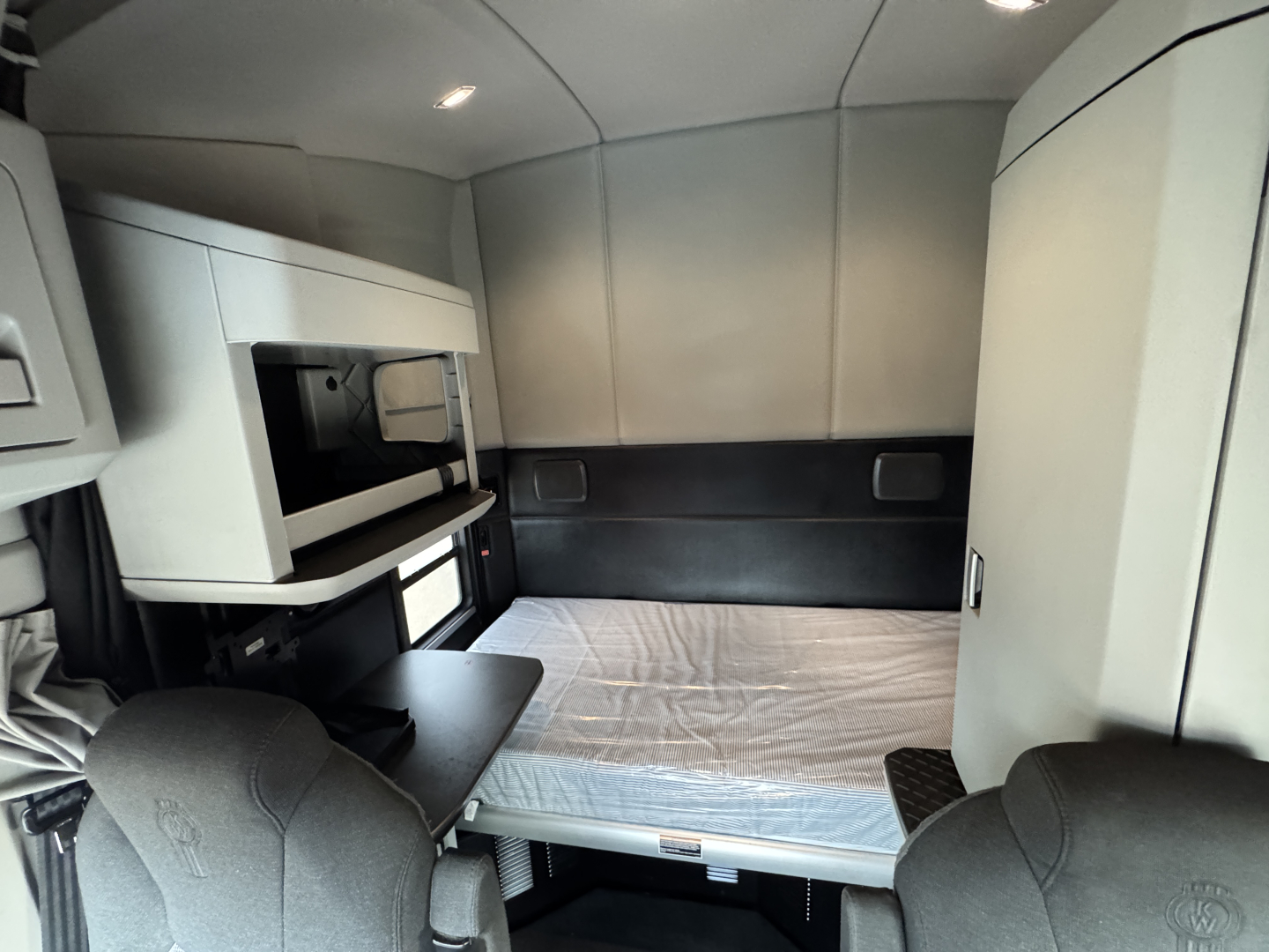 Interior cab of a 2022 Kenworth T680 sleeper truck showing bunk bed and storage cabinets.