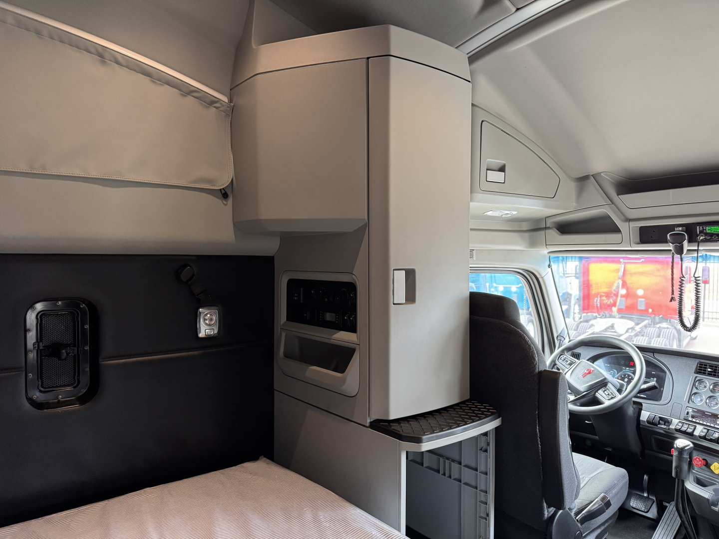 Kenworth T680 sleeper cab interior with overhead storage and dashboard visible.