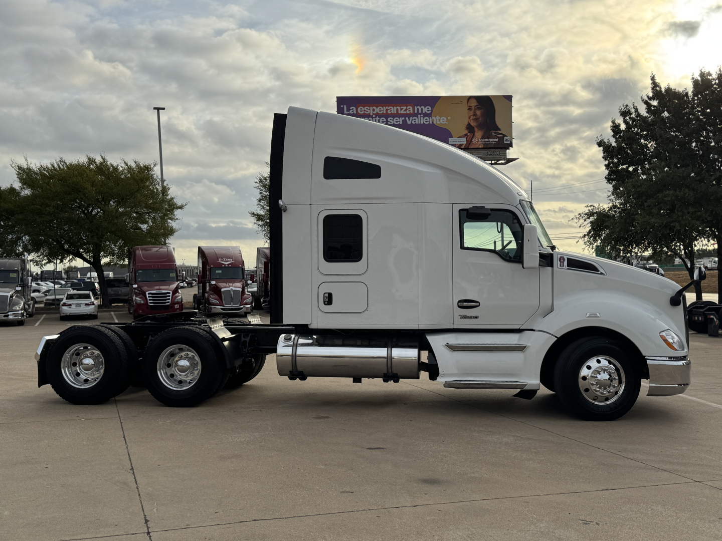 Kenworth T680 tractor side view showing sleeper cab, dual rear axles, white exterior.