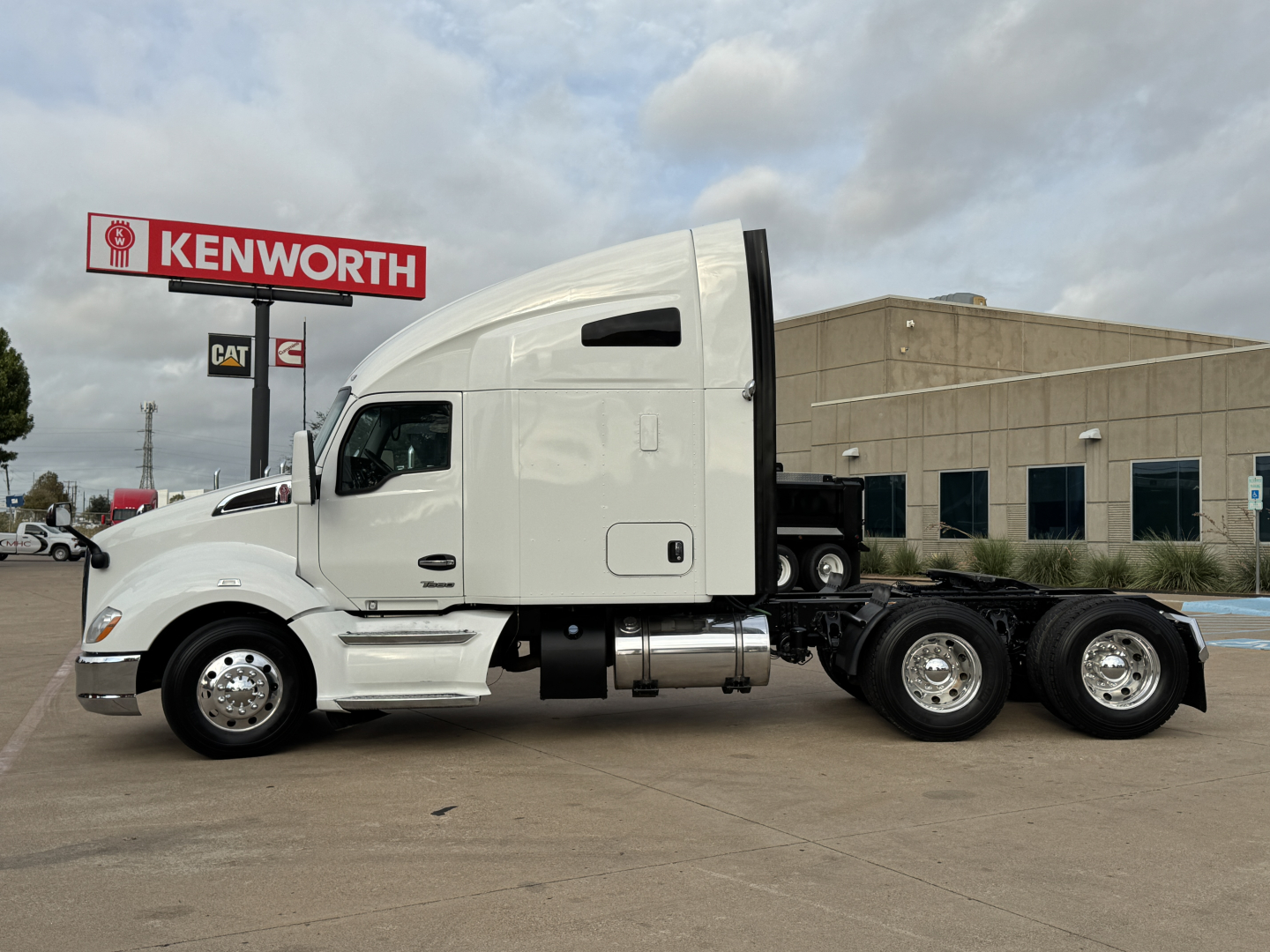 Kenworth T680 sleeper tractor in white, side view showing cab, fuel tanks, and dual rear axles.