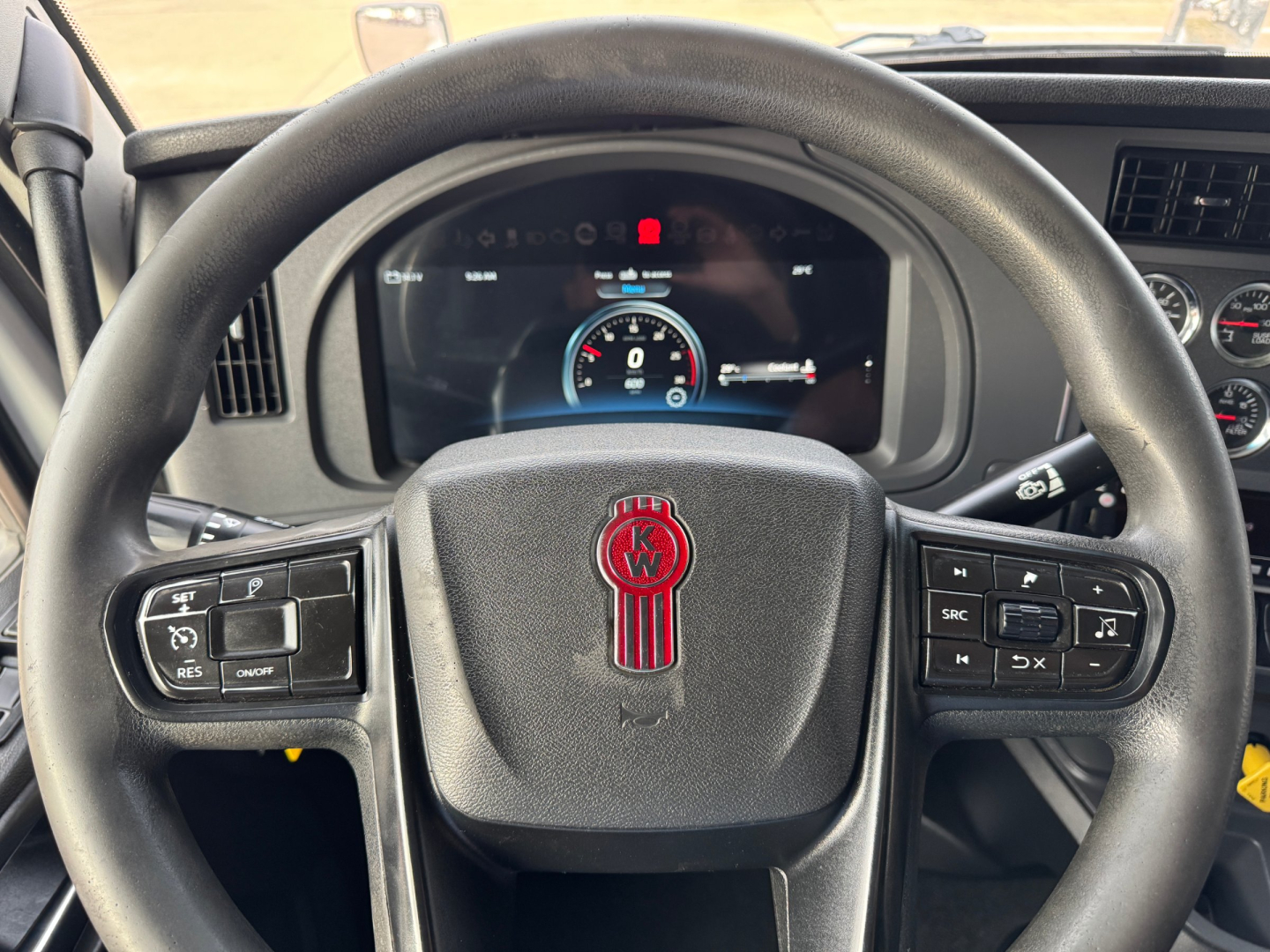Kenworth T680 steering wheel and dashboard view showing instrument cluster and control buttons.