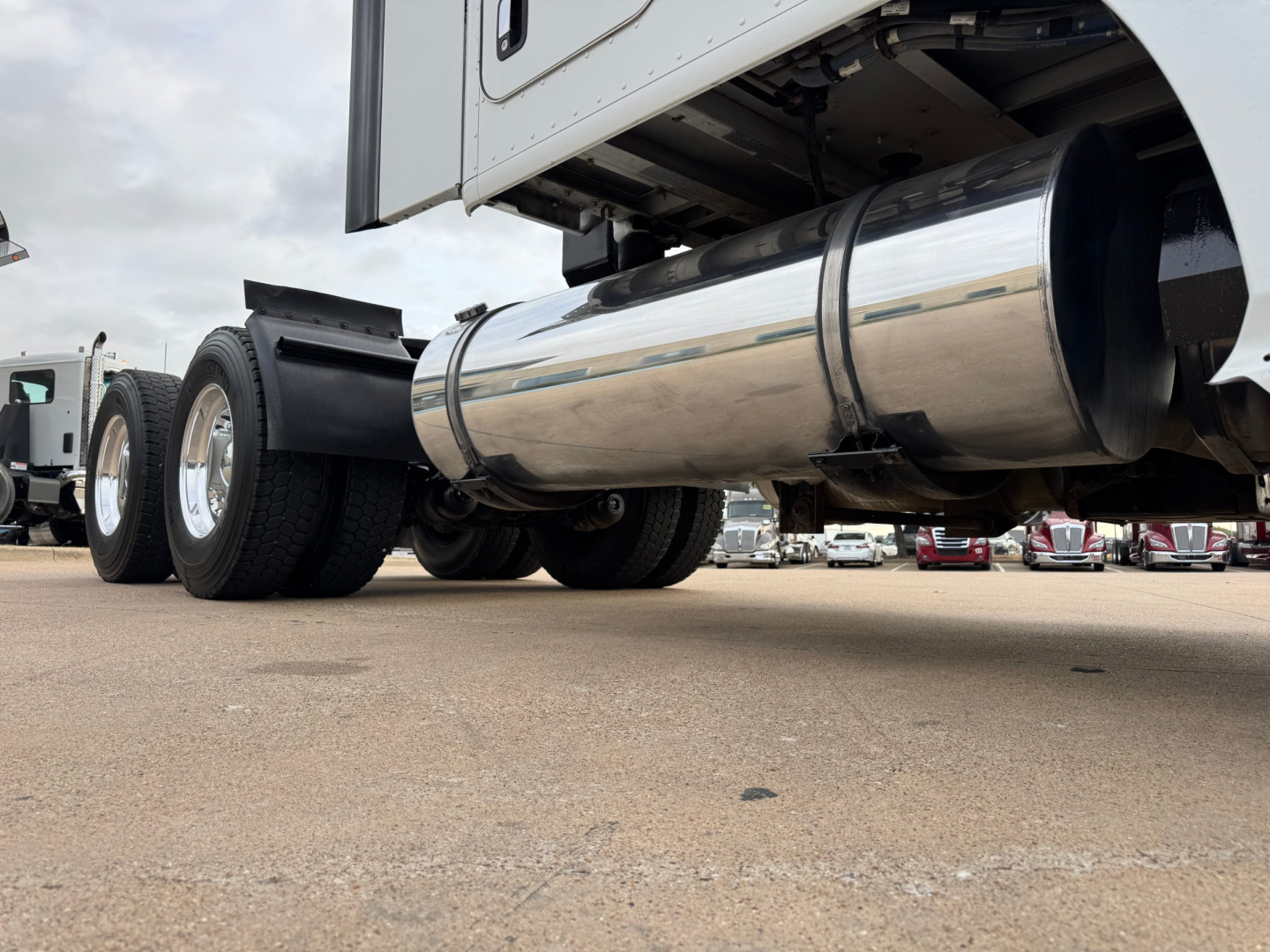 Kenworth truck undercarriage showing polished cylindrical exhaust/muffler and rear dual wheels.