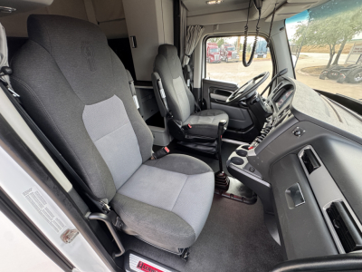 Truck cab interior of a 2022 Kenworth T680 showing driver's seat and passenger seat, dashboard, steering wheel, and center console.