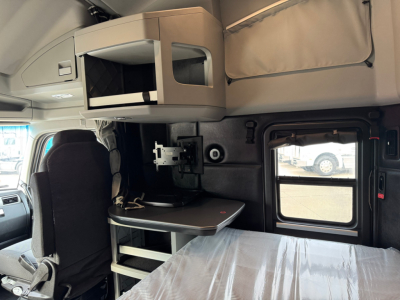 Kenworth T680 cab interior with sleeper bunk area, overhead storage, fold-out table, window, and seat visible.