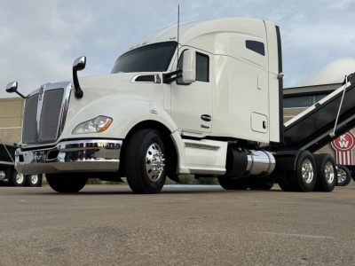 Kenworth T680 conventional sleeper truck side view showing white cab and chrome grille with dual fuel tanks.