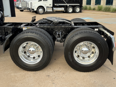 Kenworth T680 chassis with dual rear axles and polished chrome wheels, visible frame and fuel tanks in foreground.