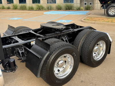 Kenworth T680 chassis rear view showing dual rear axles and chrome wheels, with visible frame and suspension components.