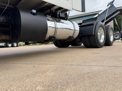 Kenworth T680 side view showing polished cylindrical fuel tank and dual rear axles under the trailer.