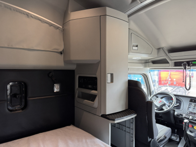 Kenworth T680 sleeper cab interior with overhead storage and dashboard visible.