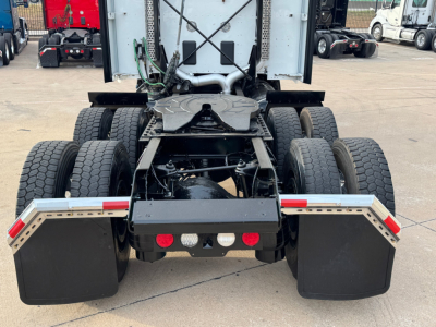 Kenworth T680 rear view showing dual rear axles and mud flaps, chassis and fifth-wheel area visible, with red taillights and reflective tape.