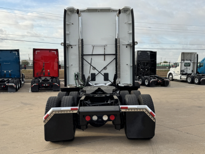 Kenworth T680 rear view showing chassis and dual rear axles under a sleeper cab, with mud flaps and bumper lights visible.
