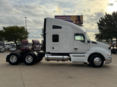 Kenworth T680 tractor side view showing sleeper cab, dual rear axles, white exterior.