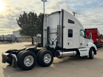 Kenworth T680 sleepered tractor, side view showing dual rear axles, white cab, chrome fuel tank, and fifth-wheel area.
