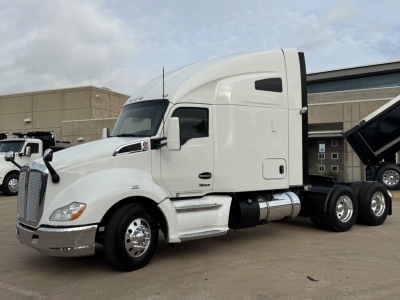 Kenworth T680 tractor unit side view showing sleeper cab, dual rear axles, and fuel tanks; white exterior with chrome accents.