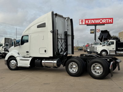 Kenworth T680 tractor in a dealership lot showing side view with sleeper cab and dual rear axles.