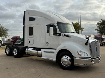 Kenworth T680 class 8 truck in white, front three-quarter view, sleeper cab, dual rear axles, chrome bumper and exhaust, during daytime.