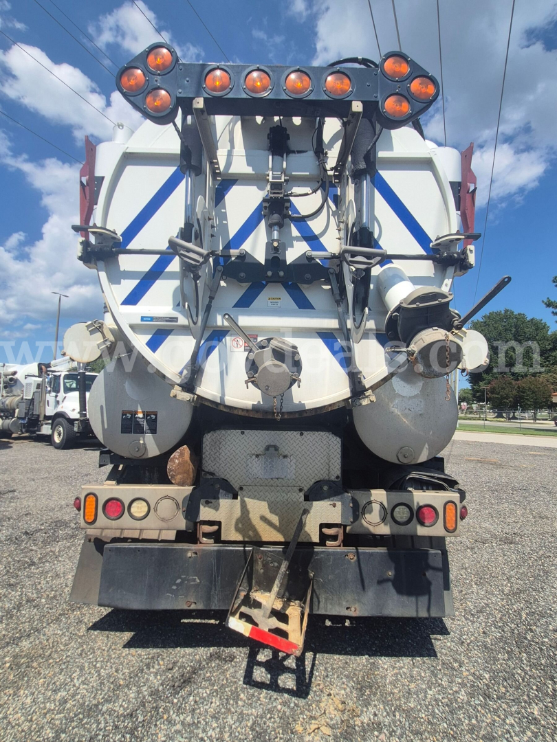 RearView of 2013 Freightliner M2 106 vacuum truck showing large white tank with blue stripe, multiple safety lights, hoses, and rear bumper.