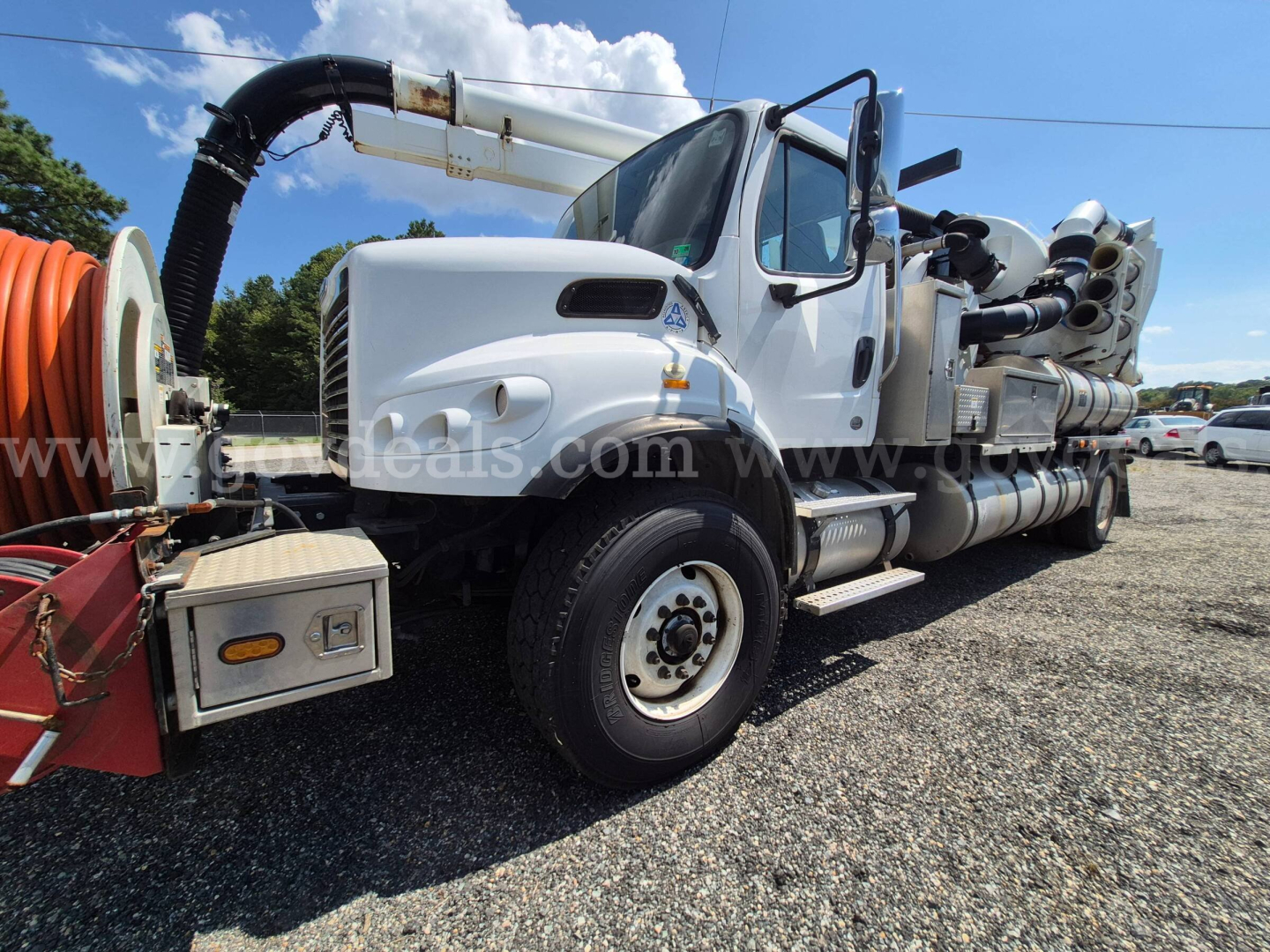 Truck side view of a 2013 Freightliner M2 106 vacuum/excavation unit with long body and attached equipment on a gravel lot.