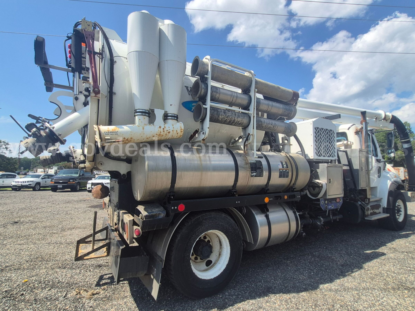Freightliner M2 106 vacuum truck rear-side view showing cylindrical tank and multiple white vertical components and exhaust stack