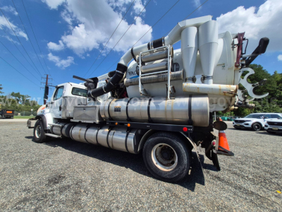 Freightliner M2 106 vacuum truck with pump assembly mounted on rear and dual fuel tanks visible, side profile view