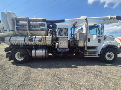 Freightliner M2 106 vacuum truck side view showing multiple cylindrical tanks and front cab with ladder steps.