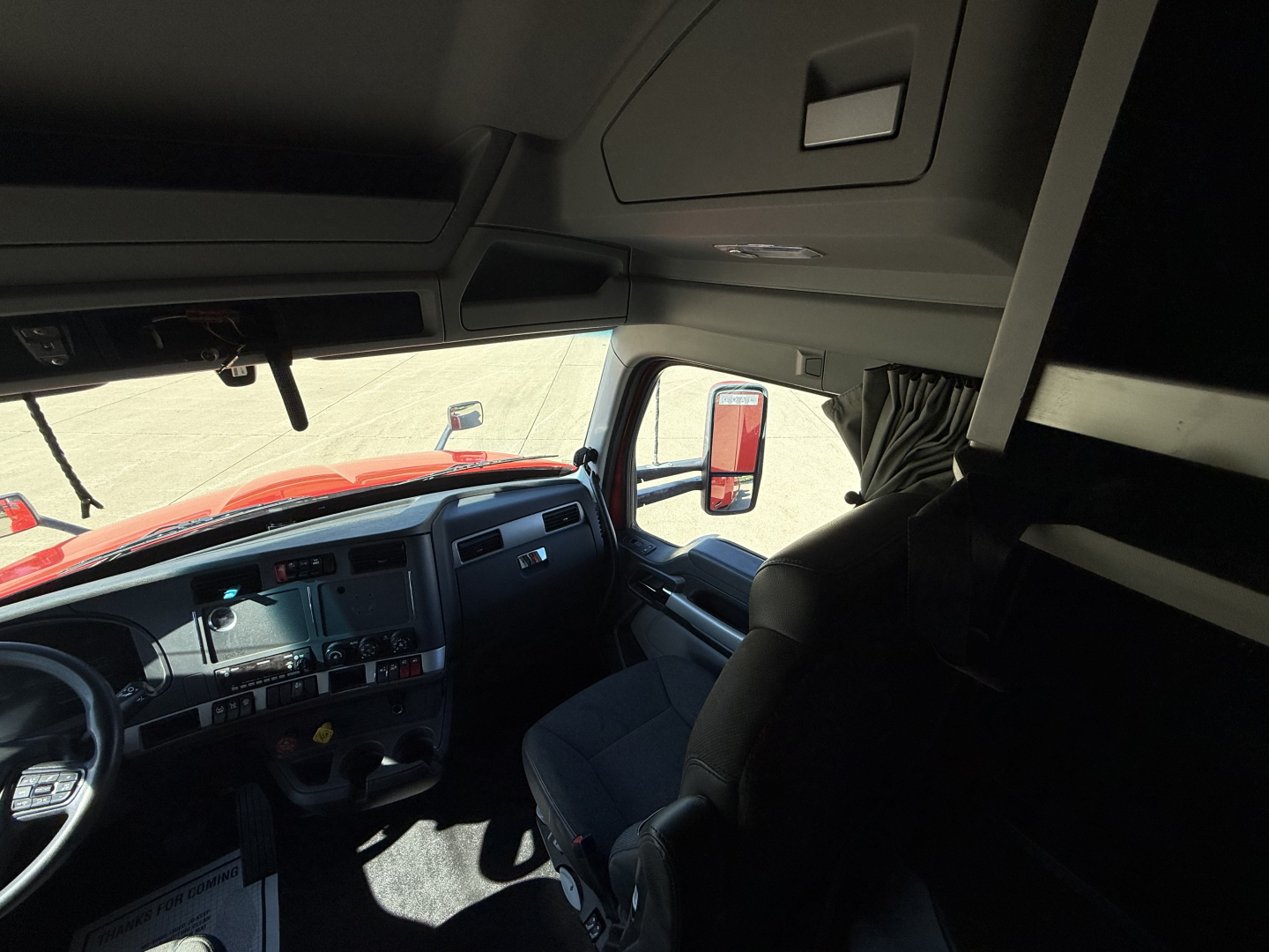 Kenworth T680 cab interior view from driver seat with dashboard, steering wheel, and upper sleeper berth area visible.
