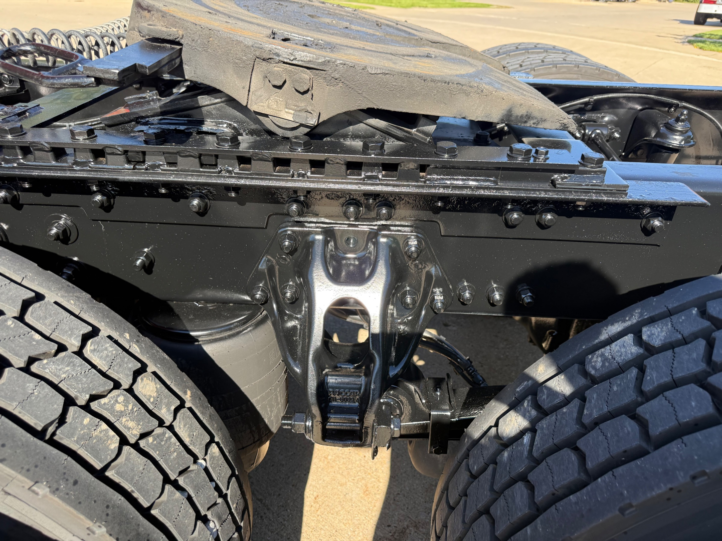 Kenworth T680 chassis underside view showing suspension hanger and frame cross member with twin rear axles visible.