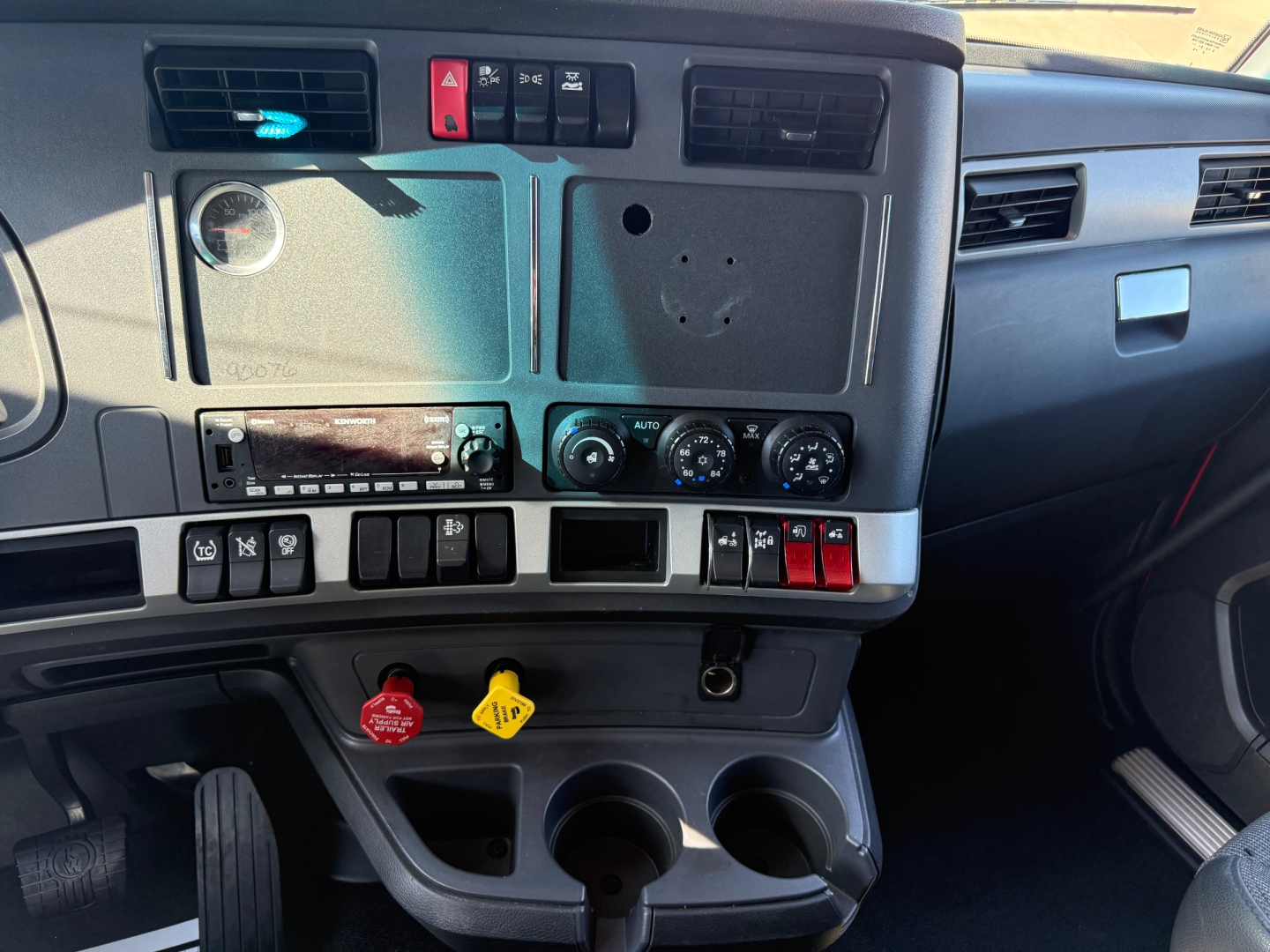 Kenworth T680 dashboard view showing control panel, ignition area, climate controls, and cup holders.