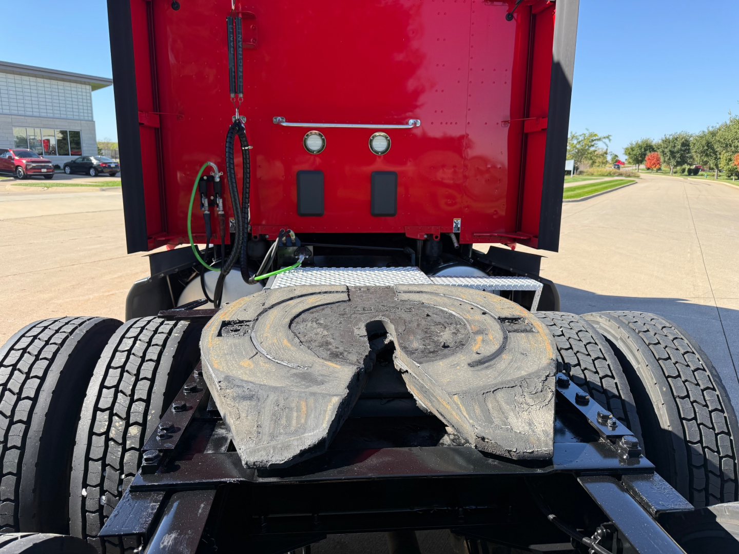 Truck fifth wheel area showing coupling area and rear of cab with red sleeper and lines.