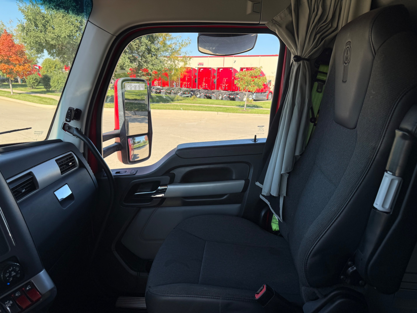 Kenworth T680 truck cab interior showing driver's seat and window view with side mirror.