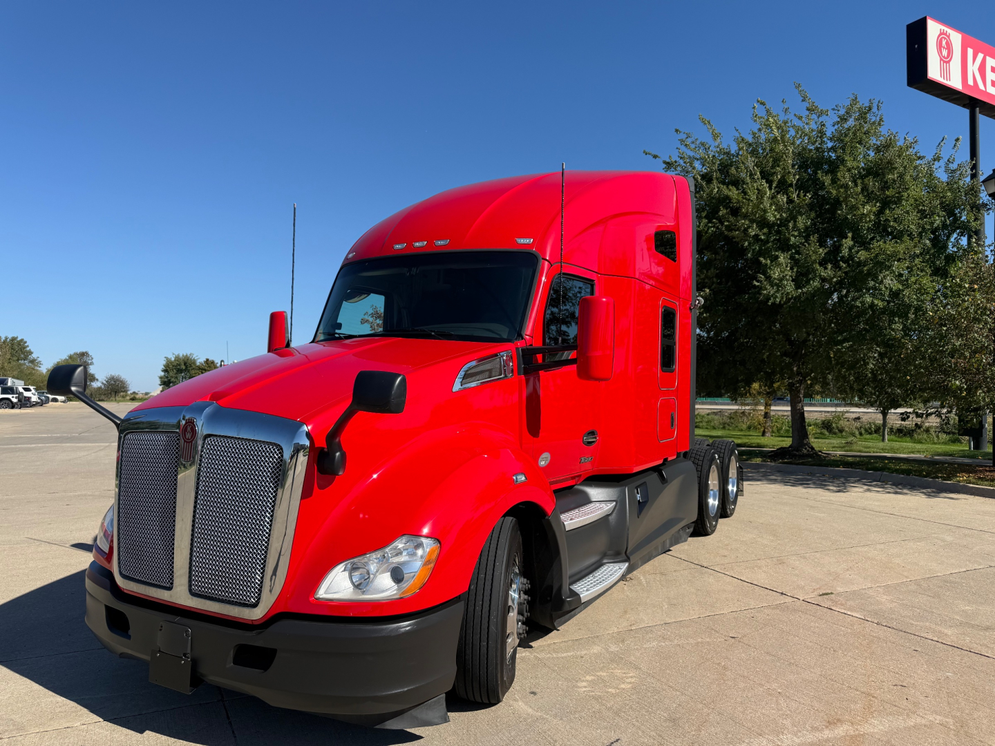 Kenworth T680 tractor truck in red color side view showing front grille and sleeper cab.