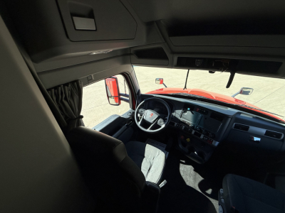 Kenworth T680 truck cabin interior view from driver seat showing steering wheel and dashboard, with windshield and side mirrors.