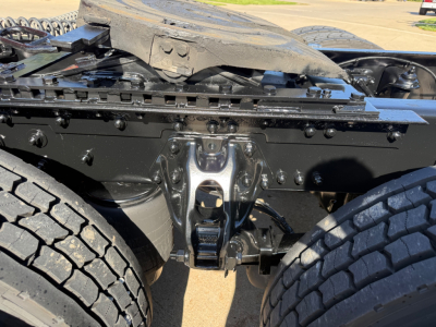 Kenworth T680 chassis underside view showing suspension hanger and frame cross member with twin rear axles visible.