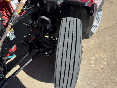 Kenworth T680 truck front view showing front axle, dual-tire configuration, and hydraulic lines near the cab; partial undercarriage visible.