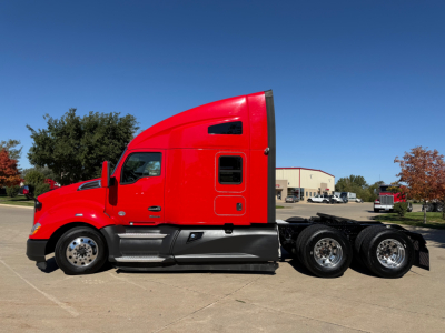 Kenworth T680 tractor unit in red side profile with sleeper cab, black lower panels, triple rear axles visible, chrome wheels.