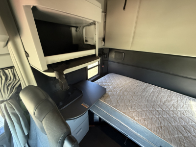 Kenworth T680 sleeper cab interior showing bunk with mattress and overhead storage cabinet.