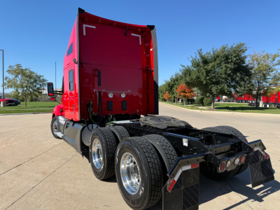 Kenworth T680 rear view showing red sleeper cab, dual rear axles, and fifth-wheel chassis with dual mud flaps.