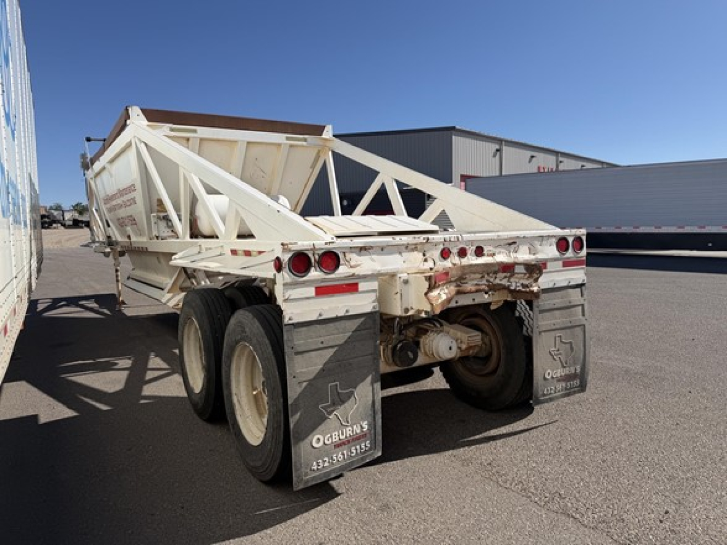 Trailer with double-axle rear view showing dump bed and rear lights.