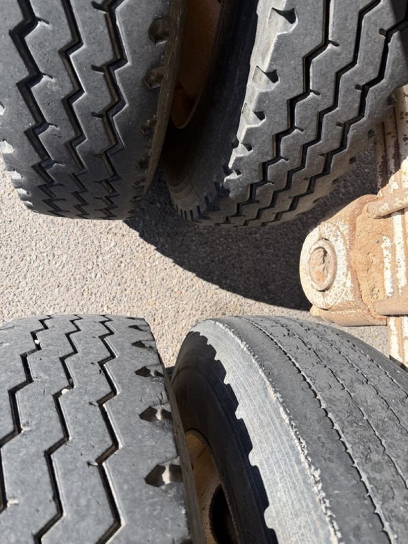 Trailer wheels close-up showing dual tires and tread pattern in a dump trailer undercarriage.