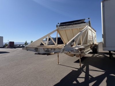 Ranco single point spring bottom dump trailer with hitch and wheel, side view showing mounting frame and hydraulic area.