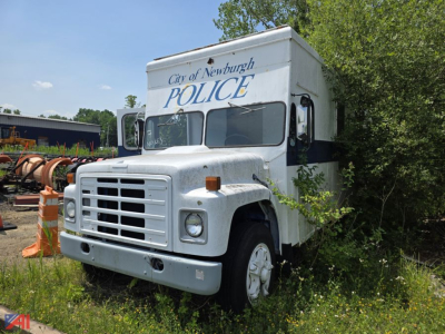 Vintage International truck front view with police box on back, City of Newburgh POLICE, utility area in background.