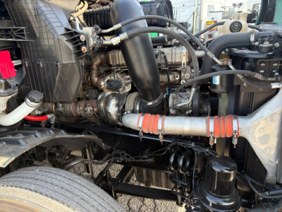 Engine bay of a Freightliner Cascadia 126 showing intake, hoses, and intercooler; label text not clearly legible.