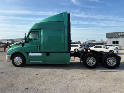 Truck side view showing a green Freightliner Cascadia 126 sleeper tractor with multiple wheels and a large fuel tank visible.