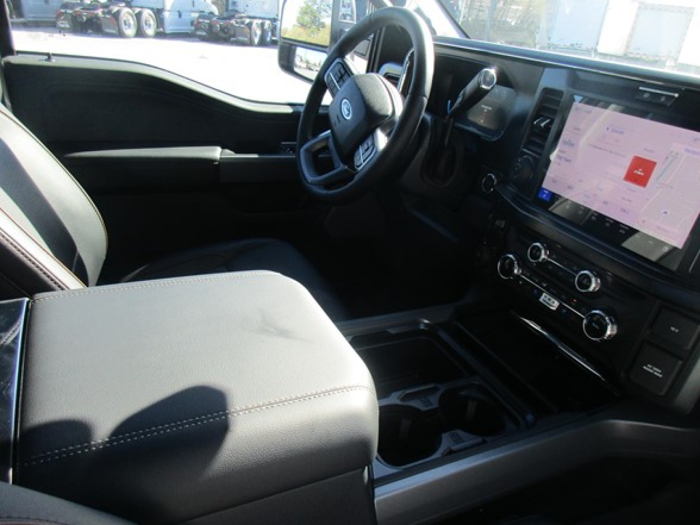 Ford F-350 interior view with steering wheel, center console, touchscreen display showing controls, and front seats.