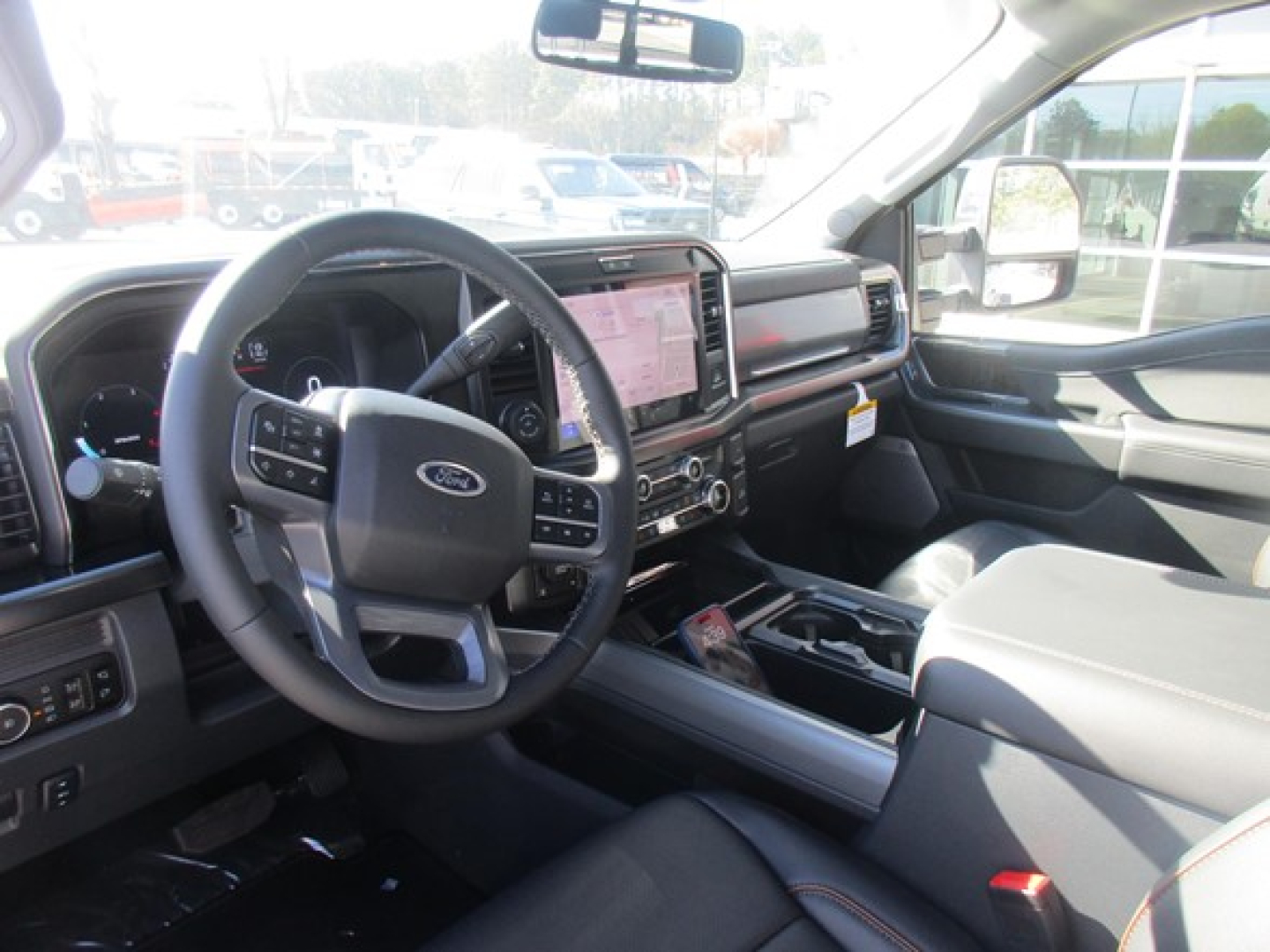 Ford F-350 interior front cabin with steering wheel, large touchscreen infotainment, center console, and driver seat; dashboard displays and controls visible.