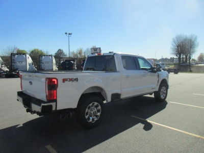 Ford F-350 pickup truck 2WD rear three-quarter view showing FX4 badge and dual exhaust. White crew cab with chrome wheels.