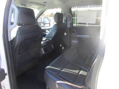 Interior of a Ford F-350 crew cab showcasing rear seats and back of front seats; light gray leather-like upholstery; window and partial view of exterior.